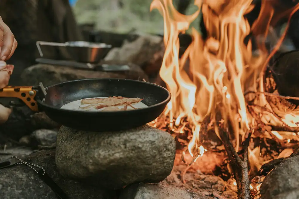 Frying pan cooking over a small campfire on a stone fire ring