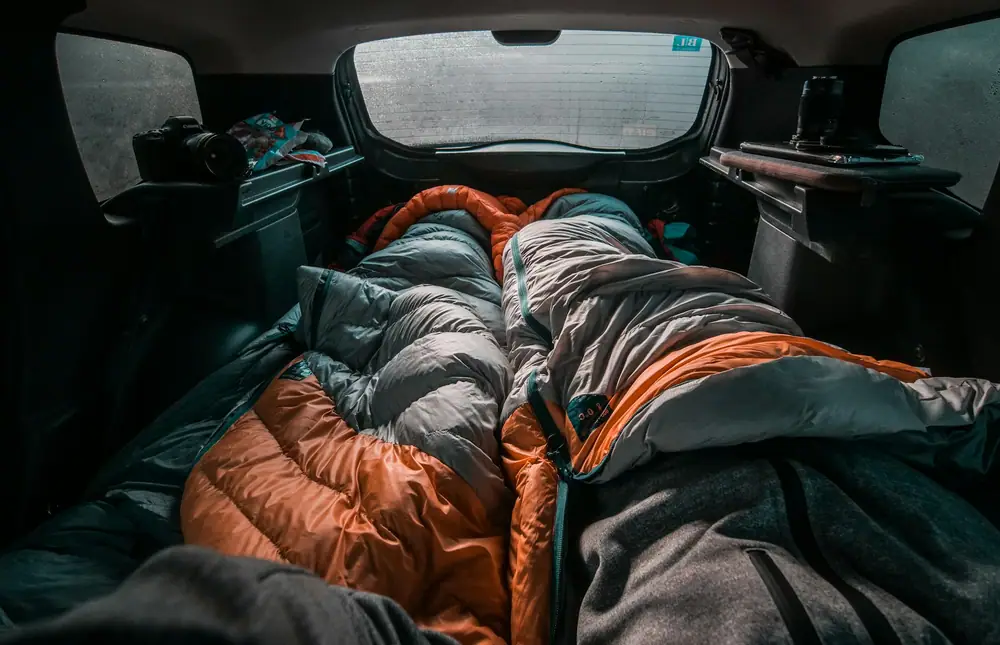 Sleeping bags and gear packed into the back of a car ready for a camping trip